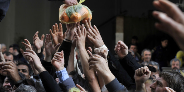 People reach out reach out for a bag of oranges during a free distribution of fruit and vegetables by Greek farmers outside the Agriculture Ministry in Athens part a farmers protest against high production costs, including petrol, on February 6, 2013. Farmers distributed more than 50 tons of fruit and vegetables. AFP PHOTO/ LOUISA GOULIAMAKI (Photo credit should read LOUISA GOULIAMAKI/AFP/Getty Images)