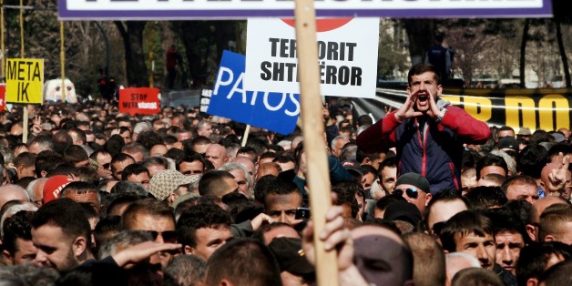 A protestor shouts slogans behind a placard reading Early Elections during a protest in front of the government building in Tirana on March 12, 2015, to demand the resignation of the Parliament speaker. The Albanian opposition requests the resignation of Parliament Speaker Ilir Meta, the junior ally in the government coalition and that of Socialist Prime Minister Edi Rama following accusations from former Socialist MP Tom Doshi, that Meta had commissioned his assassination. Meta maintains that