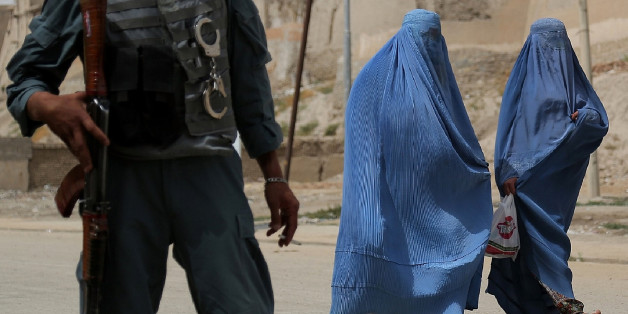 Two Afghan women walk past as a policeman stands guard in Ghazni on August 15, 2013. Taliban militants have kidnapped a female Afghan member of parliament, officials said on August 14, in the latest example of prominent women being targeted in the country. Fariba Ahmadi Kakar and her three children were taken at gunpoint on August 10 in the central province of Ghazni on the main highway from Kandahar city to Kabul. AFP PHOTO/ Rahmatullah ALIZADA (Photo credit should read RAHMATULLAH ALIZADA/AFP/Getty Images)