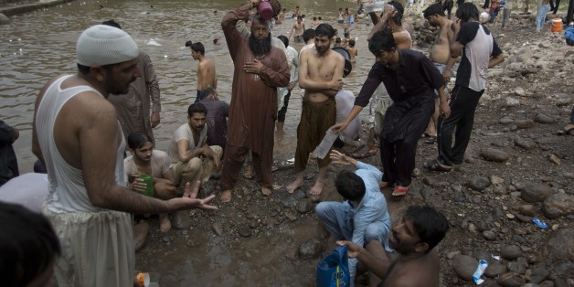 People cool themselves off at a stream in Islamabad, Pakistan as temperature increased during Ramadan, Monday, June 22, 2015. More than 100 people have died from heatstroke in the southern Pakistani port city of Karachi in the last two days, officials said Monday. (AP Photo/B.K. Bangash)