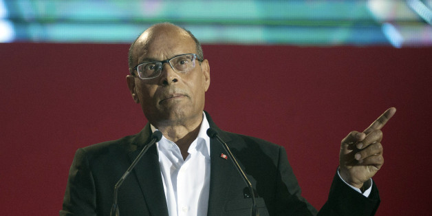 Tunisian President Moncef Marzouki, gestures as he speaks during a campaign meeting in Tunis, Tunisia, Sunday, Dec. 14, 2014. Tunisian President Moncef Marzouki will face Nidaa Tounes party leader Beji Caid Essebsi in the presidential runoff on December 21. Inscription reads, 'Tunisia will win'. (AP Photo/Aimen Zine)