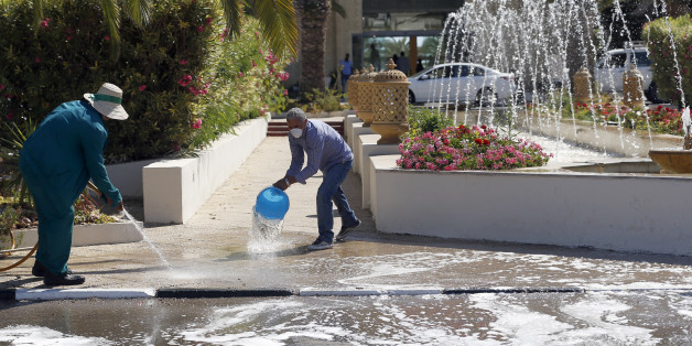 Workers clean a sidewalk in the garden of the Imperial Marhaba hotel where a shooting attack took place Friday in Sousse, Tunisia, Saturday, June 27, 2015. The morning after a lone gunman killed dozens of people at a beach resort in Tunisia, busloads of tourists are heading to the nearby Enfidha-Hammamet airport hoping to return to their home countries. (AP Photo/Darko Vojinovic)