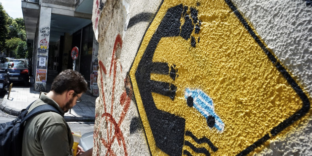 ATHENS, GREECE - JUNE 30: A man walks past anti-EU graffiti on June 30, 2015 in Athens, Greece. Greek voters will decide in a referendum next Sunday on whether their government should accept an economic reform package put forth by Greece's creditors. Greece has imposed capital controls with the banks being closed until the referendum and a daily limit of 60 euros has been placed on cash withdrawals from ATMs. (Photo by Milos Bicanski/Getty Images)
