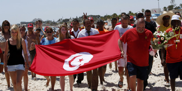 Tourists and residents, some displaying a Tunisian flag, walk on the beach to the scene of the attack in Sousse, Tunisia, Sunday, June 28, 2015. The Friday attack on tourists at a beach is expected to be a huge blow to Tunisia's tourism sector, which made up nearly 15 percent of the country's gross domestic product in 2014. (AP Photo/Abdeljalil Bounhar)