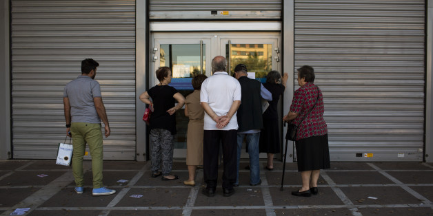 People wait to be allowed into a bank to withdraw a maximum of 120 euros ($134) for the week, in central Athens, Friday, July 3, 2015. As Greek banks and markets remain closed Friday for a fifth day, rival campaigns scrambled to roll out their messages. And a prediction from the International Monetary Fund that Greece will need piles of additional cash from eurozone countries and others over the next three years put even more pressure on the government. (AP Photo/Emilio Morenatti)