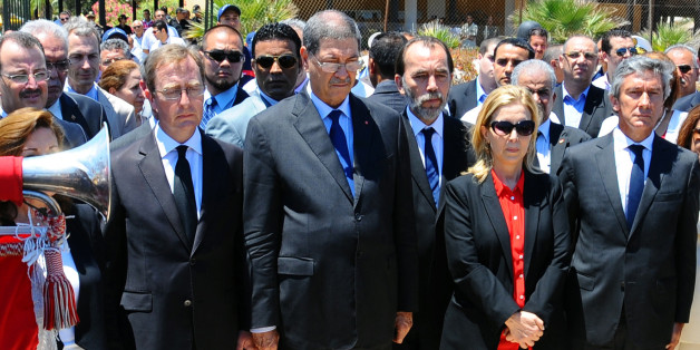 Tunisian Prime Minister Habib Essid, 2nd left, observes a one minute's silence near the Imperial Marhaba hotel in the Mediterranean resort town of Sousse, to honor the victims of a deadly beach attack a week ago that killed 38 people, Friday, July 3, 2015. Eight people are in custody in Tunisia, suspected of having direct links to a deadly beach attack that killed 38 people, but four other possible suspects have been released, a minister said Thursday. (AP Photo/Hassene Dridi)