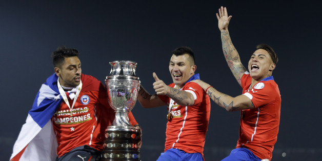 Chile's Gary Medel, center, and Chile's Eduardo Vargas, right, hold the trophy on top of the goal post after defeating Argentina in the Copa America final soccer match at the National Stadium in Santiago, Chile, Saturday, July 4, 2015. Chile became Copa America champions for the first time after defeating Argentina in a penalty shootout. (AP Photo/Ricardo Mazalan)