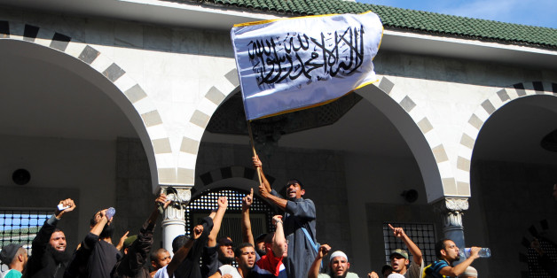 Tunisian activists stage a protest outside the El Fateh mosque surrounded by police, in support of a hardline Muslim, known as Abu Yadh, in Tunis Monday, Sept. 17, 2012. The Salafi retreated inside with dozens of supporters after a fiery denunciation of the Tunisian government. Police surrounded the mosque but did not enter. The flag with islamic inscriptions in Arabic reads : "No God but Allah, and Mohammed is his prophet". (AP Photo/Hassene Dridi)