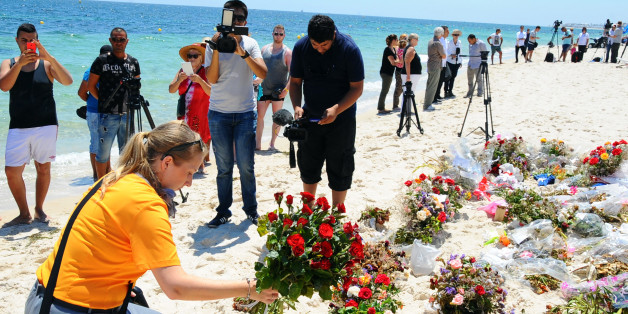 An unidentified tourist lays flowers to honor the victims of a deadly beach attack a week ago that killed 38 people, near the Imperial Marhaba hotel in the Mediterranean resort town of Sousse, Friday, July 3, 2015. Eight people are in custody in Tunisia, suspected of having direct links to a deadly beach attack that killed 38 people, but four other possible suspects have been released, a minister said Thursday. (AP Photo/Hassene Dridi)
