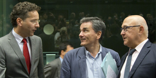 Greek Finance Minister Euclid Tsakalotos, center, speaks with Dutch Finance Minister Jeroen Dijsselbloem, left, and French Finance Minister Michel Sapin during a round table meeting of eurozone finance ministers at the EU LEX building in Brussels on Tuesday, July 7, 2015. Greek Prime Minister Alexis Tsipras was heading Tuesday to Brussels for an emergency meeting of eurozone leaders, where he will try to use a resounding referendum victory to eke out concessions from European creditors over a ba