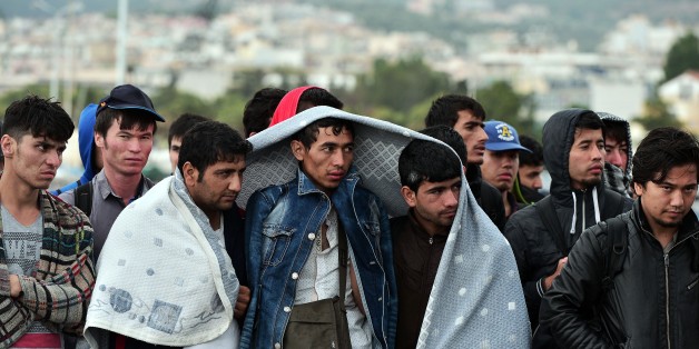 Newly arrived migrants huddle together as they try to protect themselves from the rain while waiting to be registered in Mytilene on June 19, 2015. Some 25,000 migrants and refugees mostly from Syria have descended on the Aegean island of Mytilene this year, local officials say, a fivefold increase highlighting Greece's desperate struggle to manage the influx. AFP PHOTO / LOUISA GOULIAMAKI (Photo credit should read LOUISA GOULIAMAKI/AFP/Getty Images)