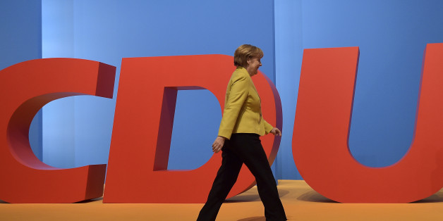 Chancellor and chairwoman of the German Christian Democrats, CDU, Angela Merkel, walks in front of a party logo during the 27th party convention in Cologne, Germany, Wednesday, Dec. 10, 2014. (AP Photo/Martin Meissner)