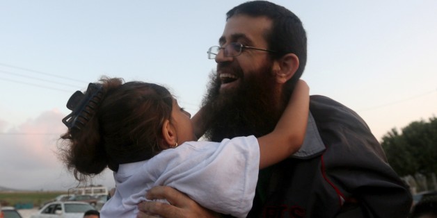 Khader Adnan, a Palestinian prisoner who staged a 56-day hunger strike while being detained for a year without charge by Israeli authorities, hugs a relative as he arrives in the West Bank village of Arraba after his release early on July 12, 2015. Adnan, 37, was detained a year ago, shortly after the kidnapping and murder of three young Israelis, which triggered the arrests of hundreds of Palestinians in the occupied West Bank. AFP PHOTO /JAAFAR ASHTIYEH (Photo credit should read JAAFAR