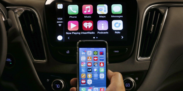 An iPhone is connected to a 2016 Chevrolet Malibu equipped with Apple CarPlay apps, displayed on the car's MyLink screen, top, during a demonstration in Detroit, Tuesday, May 26, 2015. Starting with Chevrolet this summer, many General Motors models will offer Appleâs CarPlay and Googleâs Android Auto systems that link smart phones with in-car screens and electronics. (AP Photo/Paul Sancya)