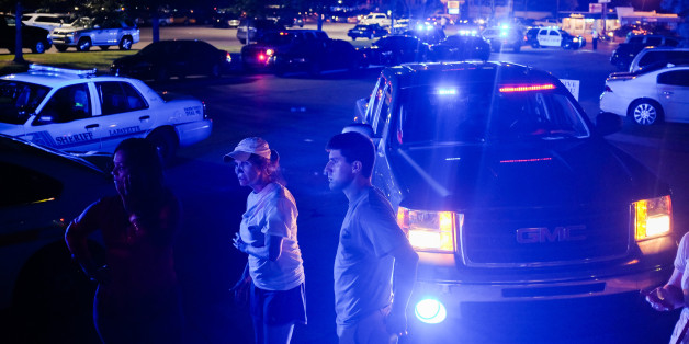 Bystanders look on as emergency personnel respond to the scene of a deadly shooting at the Grand Theatre in Lafayette, La., Thursday, July 23, 2015. (AP Photo/Denny Culbert)