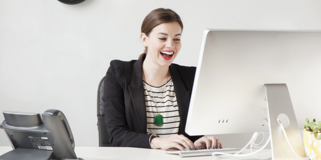 Studio shot of young woman working on computer and laughing