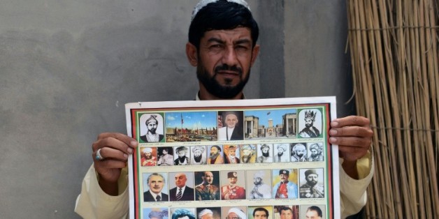 Un afghan montre un calendrier ou figurent les photographies des leaders afghans, y compris le dernier chef des talibans le mollah Omar, à Kandahar le 31 juillet 2015