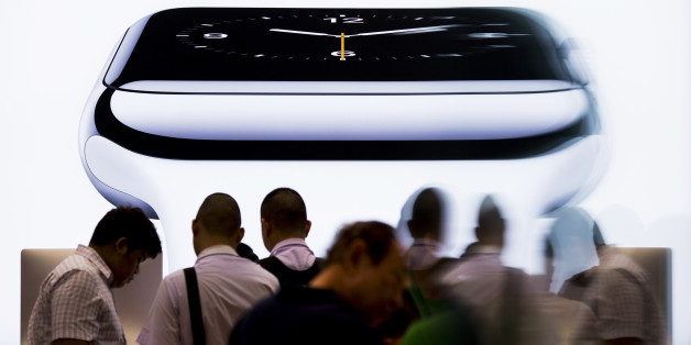 Customers are reflected in glass as they queue in front of an illuminated Apple Inc. Apple Watch display at an iStudio store in Bangkok, Thailand, on Friday, July 17, 2015. Apple's silence on demand for its smartwatch is making it harder for analysts to gauge whether the wearable gadget is performing successfully. Yet even low estimates suggest the timepiece could become a bestseller. Photographer: Brent Lewin/Bloomberg via Getty Images