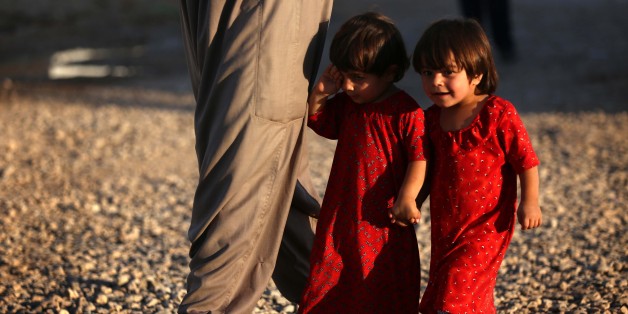 Displaced Iraqi children, who fled their homes due to attacks by the Islamic State (IS) group, walk at the Harsham refugee camp where they found shelter, ten kilometres west of Arbil, the capital of the autonomous Kurdistan region of Iraq, on June 22, 2015. AFP PHOTO / SAFIN HAMED (Photo credit should read SAFIN HAMED/AFP/Getty Images)