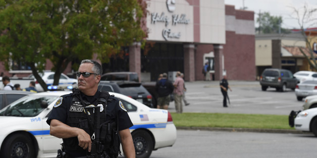 An officer stands in front of the Carmike Hickory 8 movie theater following a shooting Wednesday, Aug. 5, 2015, in Antioch, Tenn. A suspect wielding a hatchet and a gun inside the Nashville-area movie theater died after exchanging gunshots with a SWAT team that stormed the theater, police said. (AP Photo/Mark Zaleski)