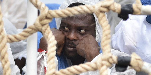 A migrant shelters from rain as he waits to disembark from Italian Coast Guard ship Oreste Corsi, at the Messina harbor in Sicily, Italy, Tuesday, Aug. 4, 2015. Italyâs Coast Guard rescued 306 migrants on Tuesday, and took them safely to land in Messina as the migrants death toll for 2015 reached in August over 2000 victims, and IOM called the Channel of Sicily the deadliest route for migrants in search of a better life. (AP Photo/Carmelo Imbesi)