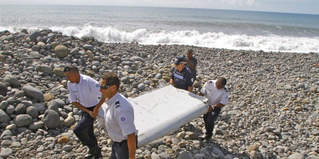 In this photo dated Wednesday, July 29, 2015, French police officers carry a piece of debris from a plane in Saint-Andre, Reunion Island. Air safety investigators, one of them a Boeing investigator, have identified the component as a "flaperon" from the trailing edge of a Boeing 777 wing, a U.S. official said. Flight 370, which disappeared March 8, 2014, with 239 people on board, is the only 777 known to be missing. (AP Photo/Lucas Marie)