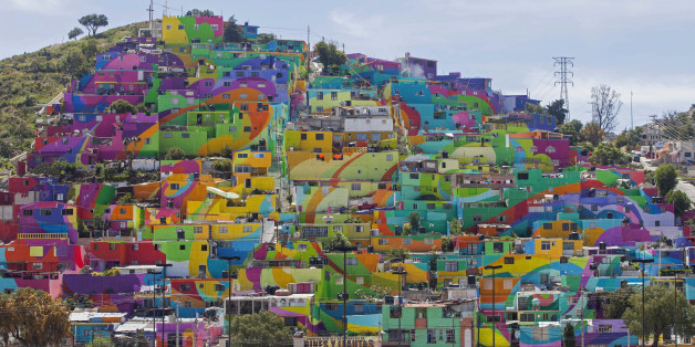 In this Thursday, July 30, 2015 photo, hundreds of houses painted in bright colors in what organizers claim is Mexico's largest mural, is part of a government-sponsored project is called Pachuca Paints Itself, in the Palmitas neighborhood, in Pachuca, Mexico. German Crew is the artist collective responsible for painting the mural project. Director Enrique Gomez, who goes by MYBE, said the crew has painted 1,500 square meters with 20,000 liters of paint. The project aims to bring the community together and rehabilitate the area. (AP Photo/Sofia Jaramillo)