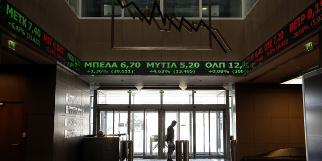 A man walks at the reception hall of the Athens' Stock Exchange as stock prices are on display on a ticker screen in Athens, Greece, on Tuesday, Aug. 4, 2015. The Stock Exchange is suffering a second day of losses after reopening amid capital controls, with banks again suffering the worst damage. (AP Photo/Yorgos Karahalis)