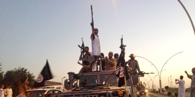 FILE - In this photo taken Monday, June 23, 2014, fighters from the Islamic State group parade in a commandeered Iraqi security forces armored vehicle down a main road at the northern city of Mosul, Iraq. An independent monitoring group says some bombings carried out by the U.S.-led coalition targeting the Islamic State group likely have killed hundreds of civilians. The coalition had no immediate comment on the report released Monday, Aug. 3, 2015. (AP Photo, File)