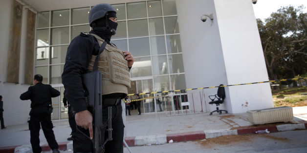 Policemen guard the entrance of the Bardo museum in Tunis, Tunisia, Thursday, March 19, 2015, as a a blood stain is seen at right, a day after gunmen opened fire killing over 20 people, mainly tourists. One of the two gunmen who killed tourists and others at a prominent Tunisian museum was known to intelligence services, Tunisia's prime minister said Thursday. But no formal links to a particular terrorist group have been established in an attack that threatens the country's fledgling democracy and struggling tourism industry. (AP Photo/Christophe Ena)