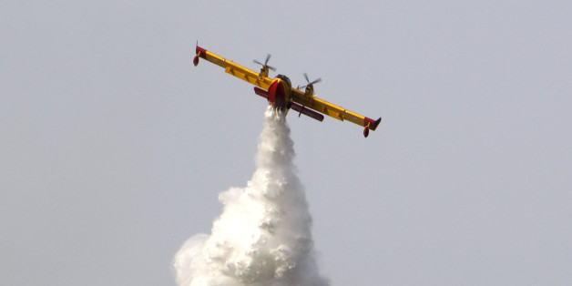 A Canadair plane helps to battle a forest fire near the village of Panaktos, some 40 kilometers (25 miles) northwest of Athens on Tuesday, July 15, 2008. Firefighters battled to stop a forest fire reaching a munitions factory authorities said. The Fire Service said at least one home was destroyed in the blaze and several others were damaged.(AP Photo/Thanassis Stavrakis)