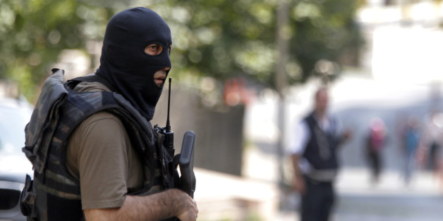 A masked Turkish police officer secures a road leading to the U. S. Consulate building in Istanbul, Monday, Aug. 10, 2015. Two assailants opened fire at the building on Monday, touching off a gunfight with police before fleeing the scene, Turkish media reports said. (AP Photo/Lefteris Pitarakis)
