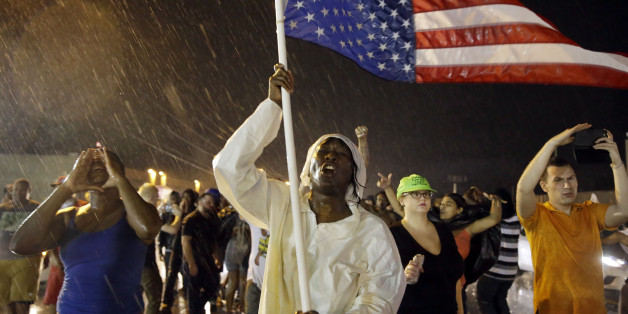 Protesters march in the rain, Sunday, Aug. 9, 2015, in Ferguson, Mo. Sunday marks one year since Michael Brown was shot and killed by Ferguson Police Officer Darren Wilson. (AP Photo/Jeff Roberson)