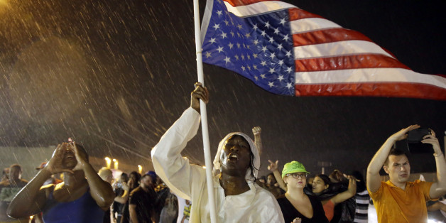 Protesters march in the rain, Sunday, Aug. 9, 2015, in Ferguson, Mo. Sunday marks one year since Michael Brown was shot and killed by Ferguson Police Officer Darren Wilson. (AP Photo/Jeff Roberson)