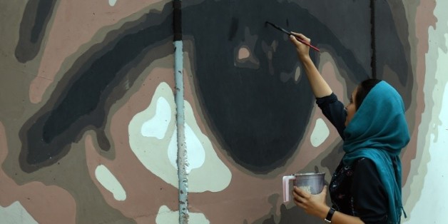 Une artiste afghane peint un oeil géant sur un mur de de protection du palais présidentiel de Kaboul pour dénoncer la corruption dans son pays, le 21 juillet 2015