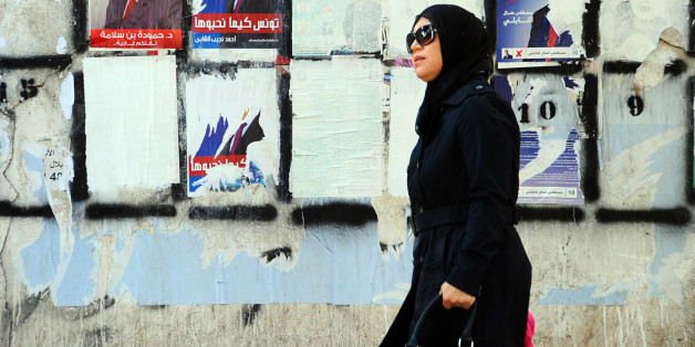 A woman walks past a wall plastered with electoral campaign posters two days before the first round of the presidential elections in Tunis, Tunisia, Friday, Nov. 21, 2014. Tunisia's presidential election represents the final phase in a torturous and difficult transition to democracy since Tunisians overthrew Ben Ali in January 2011 â sparking the Arab Spring protests that ousted autocrats across the Middle East. (AP Photo/Hassene Dridi)