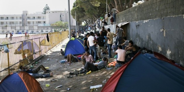 Des migrants attendent à l'extérieur du stade de l'île de Kos avant de pouvoir se faire enregistrer administrativement en Grèce, le 12 août 2015