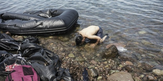 Un syrien embrasse la terre à son arrivée sur l'île grecque de Lesbos, le 14 août 2015 après avoir traversé la mer Egée en partant de Turquie