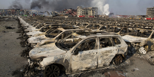 Smoke billows from the site of an explosion that reduced a parking lot filled with new cars to charred remains at a warehouse in northeastern China's Tianjin municipality, Thursday, Aug. 13, 2015. Huge, fiery blasts at a warehouse for hazardous chemicals killed many people and turned nearby buildings into skeletal shells in the Chinese port of Tianjin, raising questions Thursday about whether the materials had been properly stored. (AP Photo/Ng Han Guan)