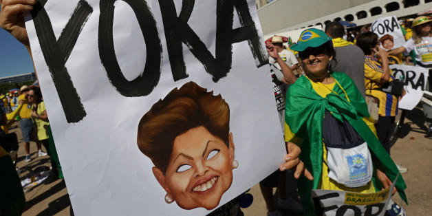 A demonstrator shows a poster that reads in Portuguese "Out" with the image of Brazil's President Dilma Rousseff, during a protest against the government of Brazil's President Dilma Rousseff, in front of the Brazilian National Congress, in Brasilia, Brazil, Sunday, Aug. 16, 2015. Demonstrators are taking to the streets across Brazil for a day of nationwide anti-government protests. President Rousseff's second term in office has been shaken by a snowballing corruption scandal involving politicia