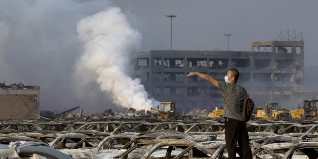 In this photo taken Thursday, Aug. 13, 2015, a man walks through the site of an explosion at a warehouse in northeastern China's Tianjin municipality. Rescuers have pulled a survivor from an industrial zone about 32 hours after it was devastated by huge blasts in Chinaâs Tianjin port. Meanwhile, authorities are moving gingerly forward in dealing with a fire still smoldering amid potentially dangerous chemicals. (AP Photo/Ng Han Guan)