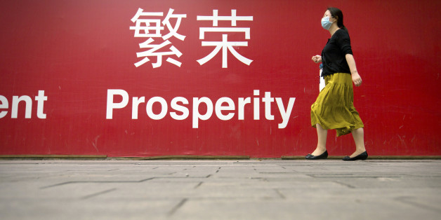 A woman walks past a banner reading "Prosperity" in English and Chinese on a street in central Beijing, Wednesday, July 15, 2015. China's economic growth in the latest quarter held steady at 7 percent, its weakest performance since the global crisis, but better retail sales and factory output in June suggested efforts to reverse the slump might be gaining traction. (AP Photo/Mark Schiefelbein)