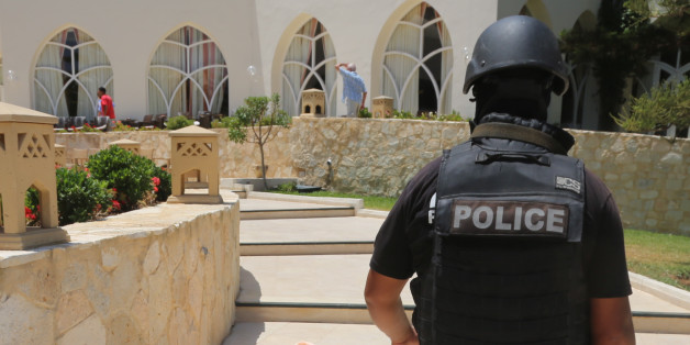 A police officer walks past a body covered near a Tunisian beach, in Sousse, Friday June 26, 2015. A young man unfurled an umbrella and pulled out a Kalashnikov, opening fire on European sunbathers in an attack that killed at least 28 people at a Tunisian beach resort â one of three deadly attacks from Europe to the Middle East on Friday that followed a call to violence by Islamic State extremists. (Jawhara FM via AP)