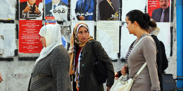 Tunisian women walk past a wall plastered with electoral campaign posters two days before the first round of the presidential elections in Tunis, Tunisia, Friday, Nov. 21, 2014. Tunisia's presidential election represents the final phase in a torturous and difficult transition to democracy since Tunisians overthrew Ben Ali in January 2011 â sparking the Arab Spring protests that ousted autocrats across the Middle East. (AP Photo/Hassene Dridi)