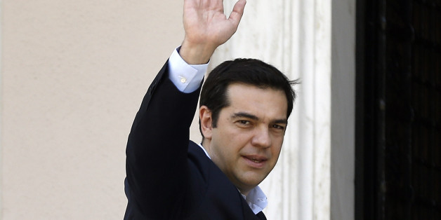 Greece's Prime Minister Alexis Tsipras waves to the media as he arrives at Maximos Mansion after a swearing in ceremony of his new ministers in Athens, Saturday, July 18, 2015. Tsipras reshuffled his Cabinet on Friday following a rebellion within his party over a parliamentary vote to approve the measures demanded for the bailout talks to start. Greek parliament approved creditor's demand for austerity measures. (AP Photo/Thanassis Stavrakis)