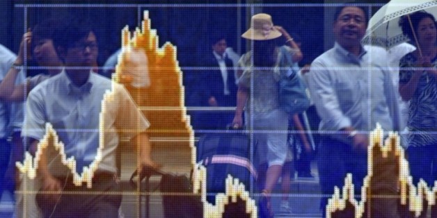 Des piétons se reflètent sur un écran de cotation à Tokyo le 24 août 2015