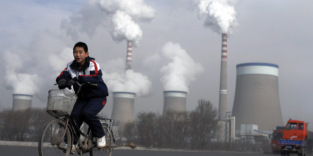 A Chinese boy cycles past a cooling towers of a coal-fired power plant in Dadong, Shanxi province, China, Thursday, Dec. 3, 2009. The U.N.'s environment chief said Tuesday he is optimistic that the climate change talks beginning in Copenhagen next week will reach a deal setting firm targets to cut carbon emissions. (AP Photo/Andy Wong)