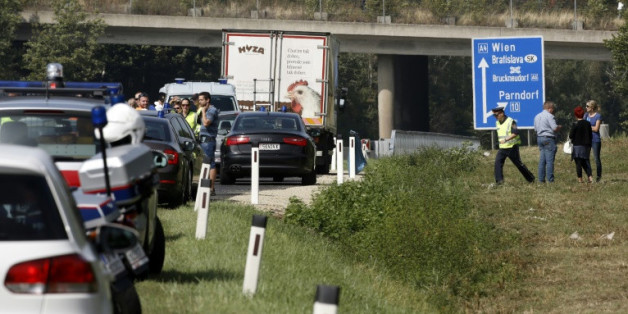 Des policiers autour du camion abandonné sur la bande d'arrêt d'urgence d'une autoroute dans lequel des corps en décomposition ont été découverts le 27 août 2015 près de Neusiedl am See en Autriche
