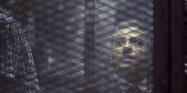 Canadian Al-Jazeera English journalist Mohammed Fahmy, listens to his verdict in a soundproof glass cage inside a makeshift courtroom in Tora prison in Cairo, Egypt, Saturday, Aug. 29, 2015. An Egyptian court on Saturday sentenced three Al-Jazeera English journalists, including Fahmy, to three years in prison, the last twist in a long-running trial criticized worldwide by press freedom advocates and human rights activists. (AP Photo/Amr Nabil)