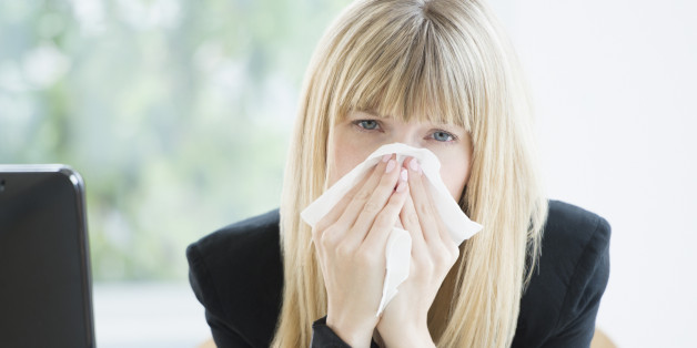 Businesswoman blowing nose in office
